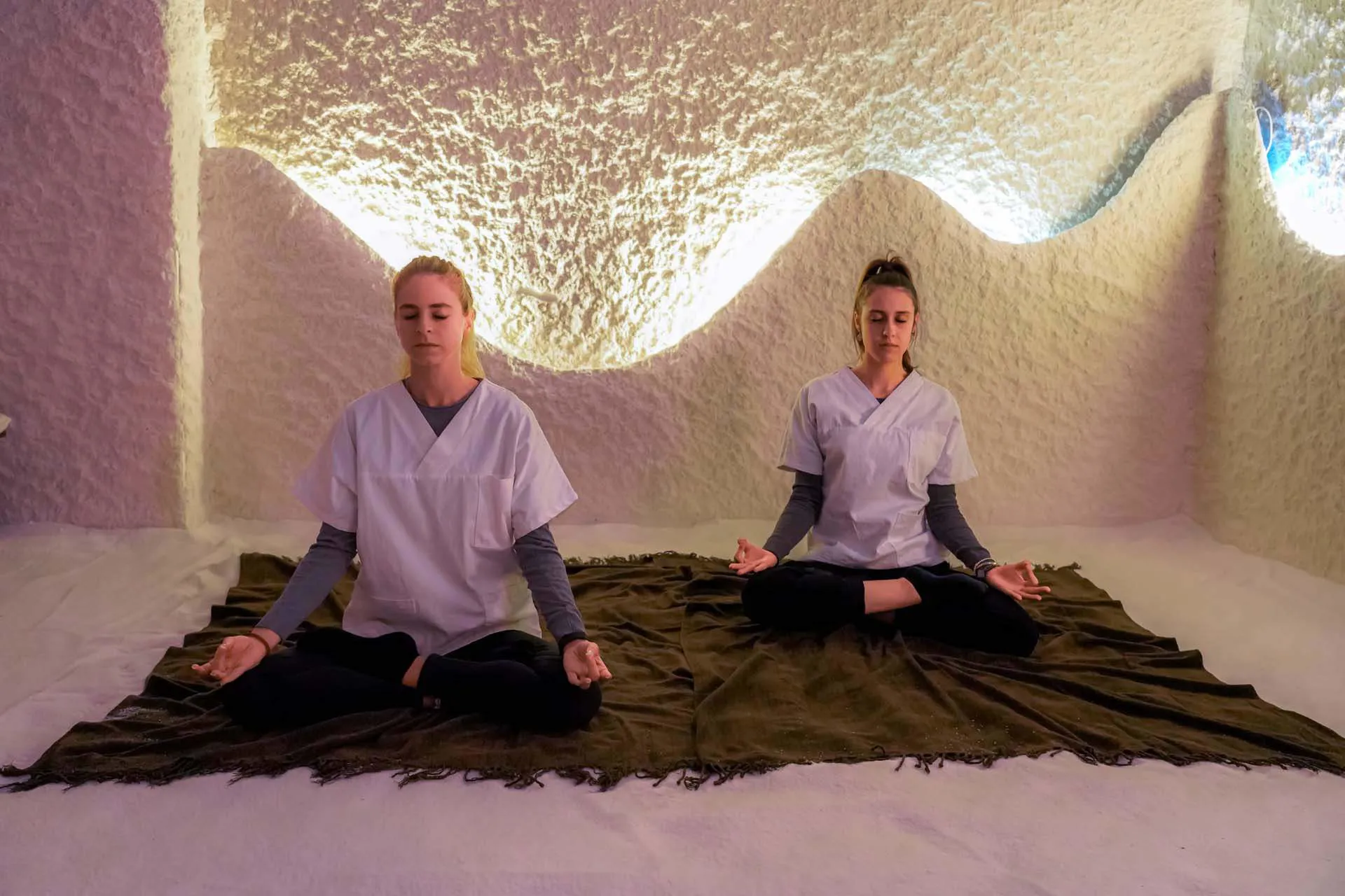 Due ragazze che fanno yoga in una grotta di sale